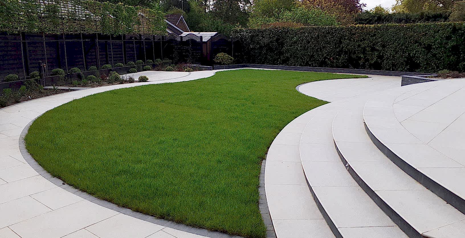 Sloping garden design Hampshire with curved steps, terraced levels, water feature, pleached trees and Porcelain paving