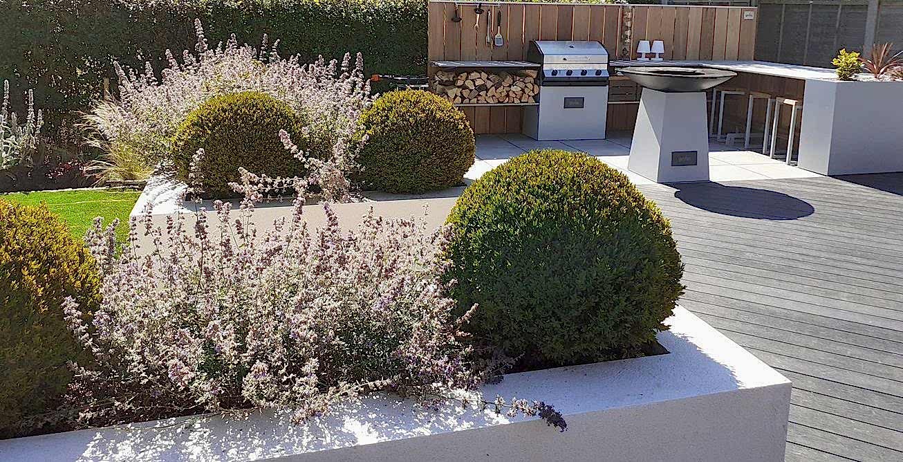 Garden design in Ascot, Berkshire with composite decking, Porcelain paving, outdoor kitchen, and raised beds.