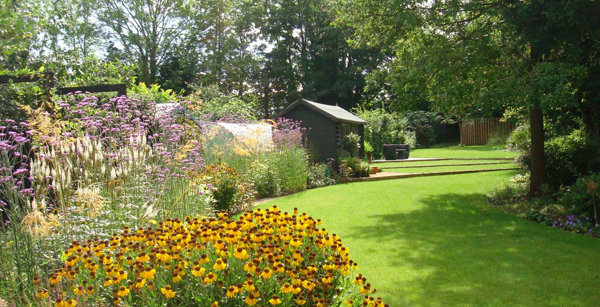 Garden design in Woking, Surrey with prarie planted borders, evening seating area, natural planting scheme, and turf steps.